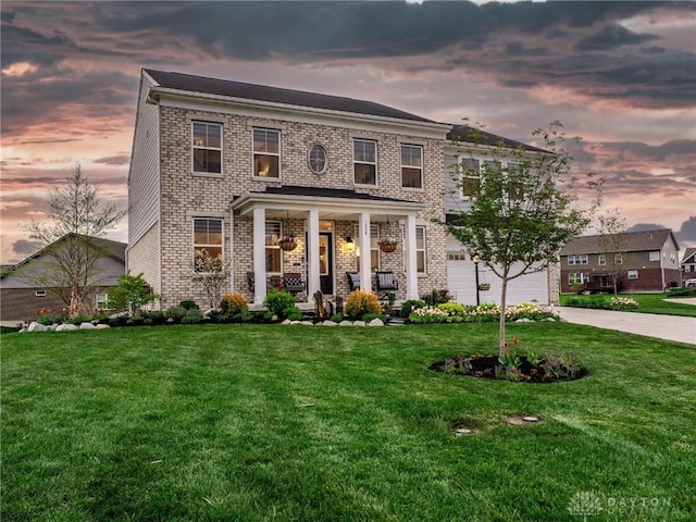 view of front of home with covered porch, an attached garage, and a front yard
