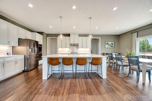 3732 Oak Creek Dr, Sugarcreek Township, OH 45440 - kitchen with appliances with stainless steel finishes, dark wood finished floors, backsplash, white cabinetry, and under cabinet range hood