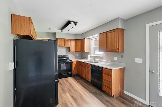 3700 Echo Hill Ln, Beavercreek, OH 45430 - kitchen with black appliances, a sink, light wood-style flooring, light countertops, and brown cabinetry