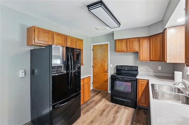 3700 Echo Hill Ln, Beavercreek, OH 45430 - kitchen with black appliances, a sink, light wood-style floors, light countertops, and brown cabinets