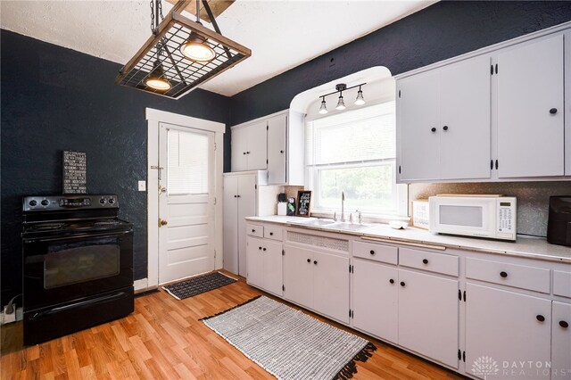 1000 Haviland Ave, Dayton, OH 45410 - kitchen featuring white microwave, black range with electric cooktop, a sink, light countertops, and light wood-style flooring