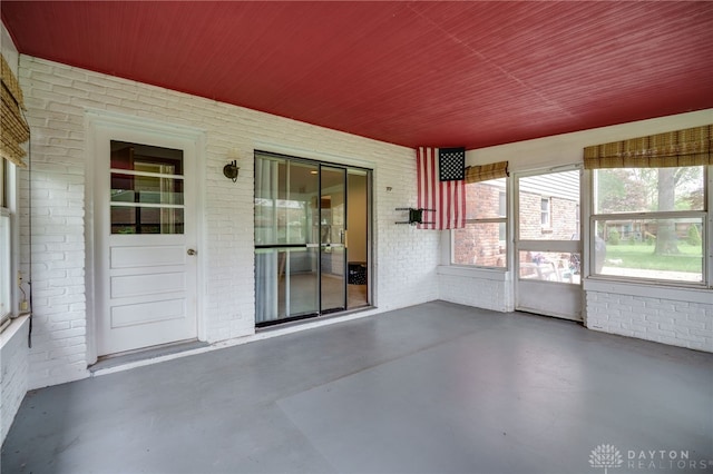 200 S Village, Washington Twp, OH 45459 - unfurnished sunroom featuring brick wall, wooden ceiling, and finished concrete flooring