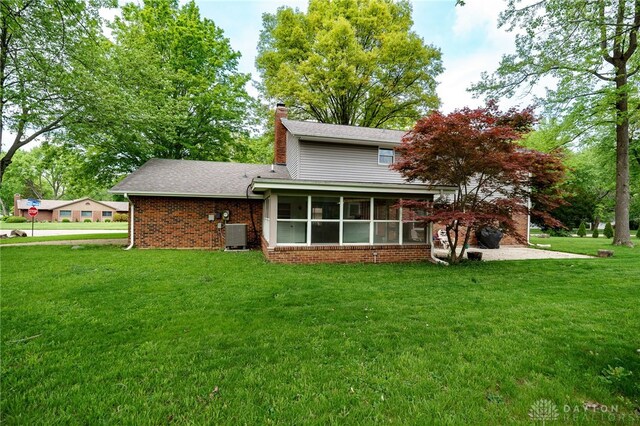 200 S Village, Washington Twp, OH 45459 - rear view of property with a chimney, a yard, a sunroom, and brick siding