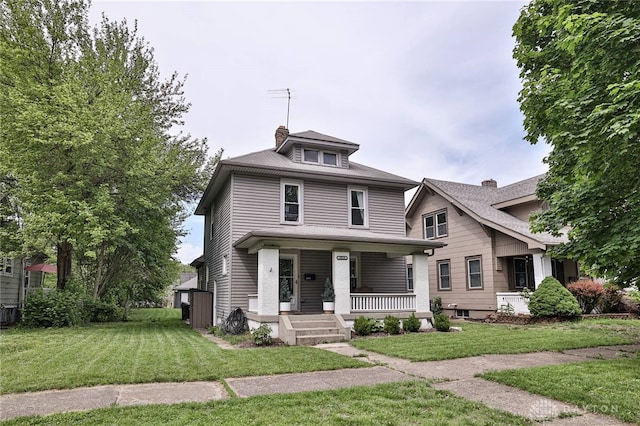 american foursquare style home with a porch, a front lawn, and a chimney