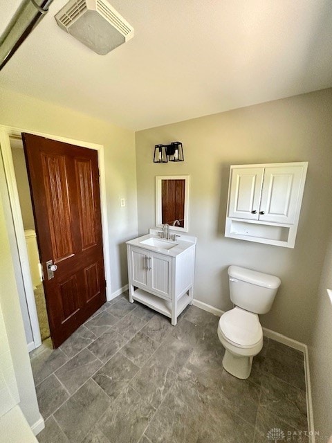 bathroom featuring toilet, vanity, and baseboards