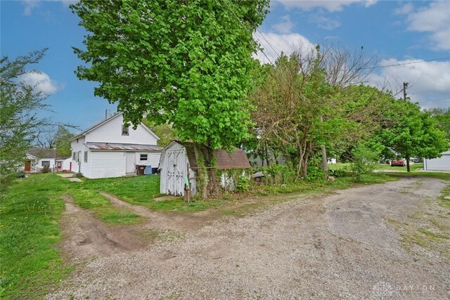 view of side of home with a storage unit, an outdoor structure, and driveway