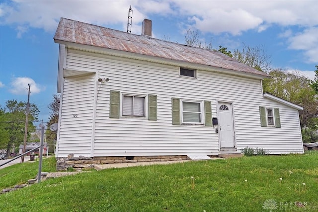 back of property featuring a yard, metal roof, and a chimney