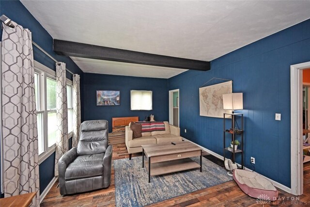 living area with wood finished floors, beam ceiling, and baseboards