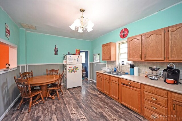 kitchen featuring freestanding refrigerator, a sink, a chandelier, dark wood finished floors, and light countertops