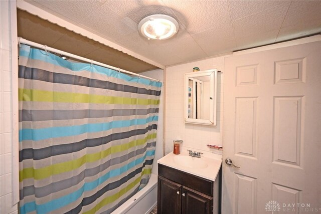 full bath with vanity, tile walls, and shower / bathtub combination with curtain