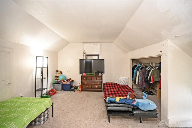 bedroom with carpet flooring, lofted ceiling, a walk in closet, and a closet