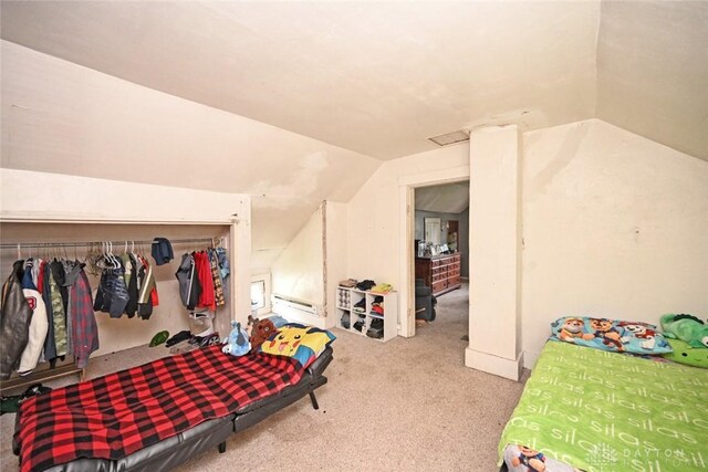 bedroom with vaulted ceiling, carpet, and a baseboard heating unit