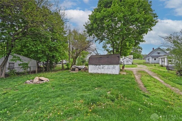 view of yard with a storage shed, an outdoor structure, and dirt driveway
