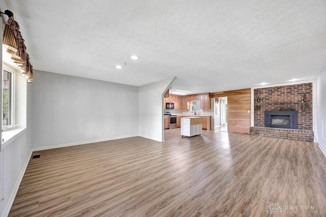 2774 N Law Rd, Oxford, OH 45056 - unfurnished living room featuring a textured ceiling, light wood finished floors, baseboards, a brick fireplace, and recessed lighting