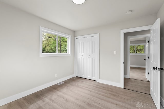 unfurnished bedroom featuring baseboards, light wood-style floors, and a closet
