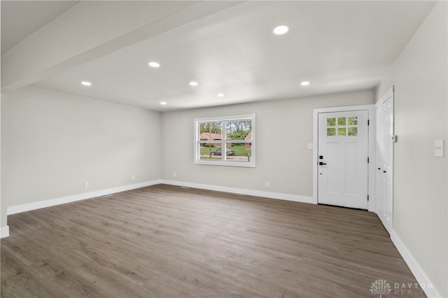 unfurnished living room featuring healthy amount of natural light, wood finished floors, baseboards, and recessed lighting