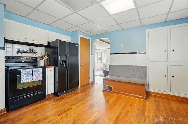 4207 Morningside Blvd, Dayton, OH 45432 - kitchen featuring black appliances, a paneled ceiling, arched walkways, light wood-style flooring, and white cabinets