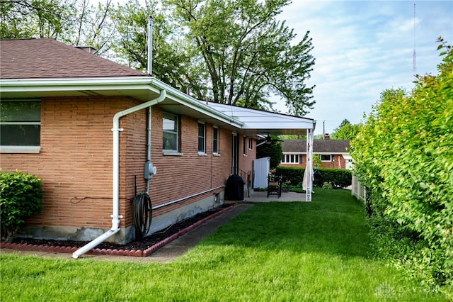 4231 Maricarr Dr, Dayton, OH 45429 - view of side of home with a lawn, brick siding, a patio area, and a shingled roof