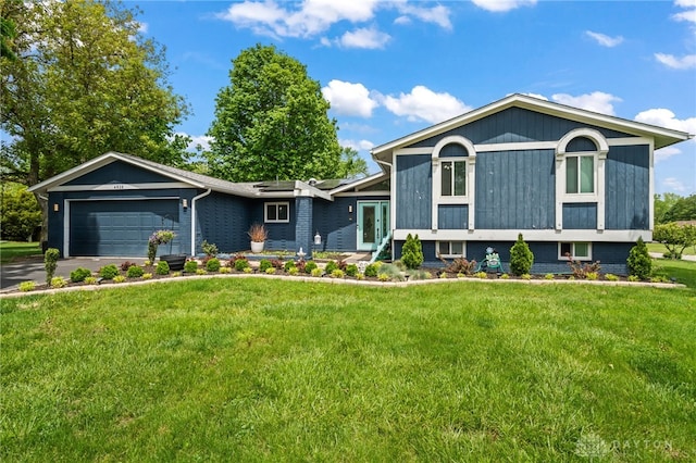 tri-level home featuring an attached garage, a front lawn, driveway, and roof mounted solar panels