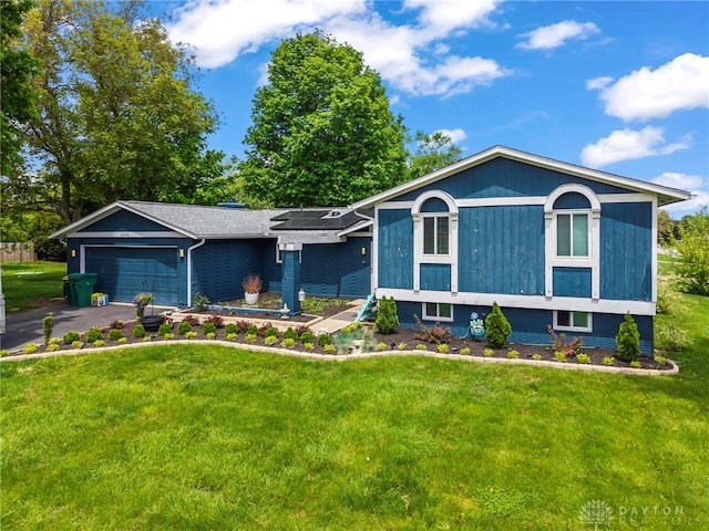 view of front of home with an attached garage, a front lawn, and driveway