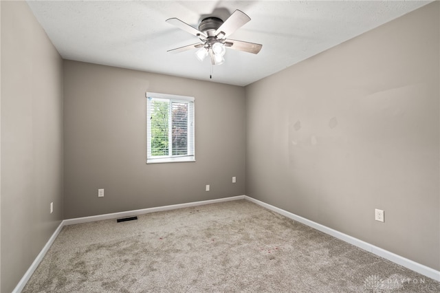 carpeted empty room featuring a ceiling fan and baseboards