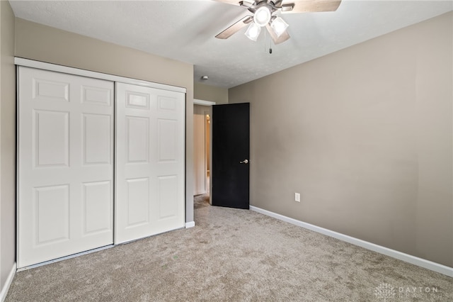 unfurnished bedroom with carpet flooring, a closet, baseboards, and ceiling fan