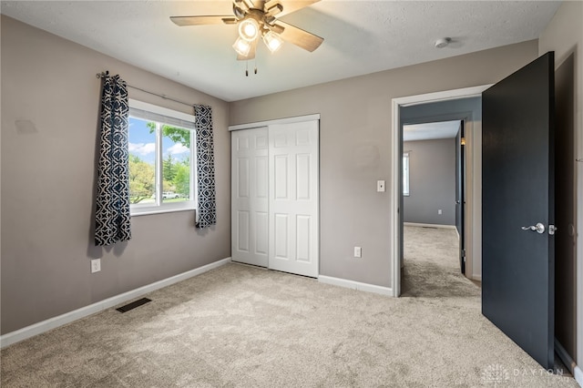 unfurnished bedroom with carpet, baseboards, a closet, and ceiling fan