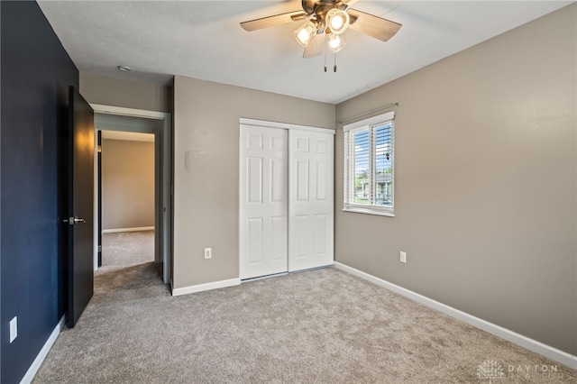 unfurnished bedroom with carpet flooring, baseboards, a closet, and ceiling fan