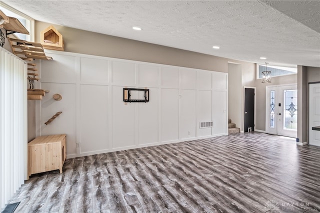 basement featuring a textured ceiling, wood finished floors, a chandelier, recessed lighting, and stairway