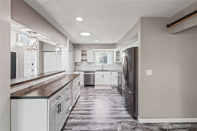 kitchen featuring appliances with stainless steel finishes, wood counters, a sink, a chandelier, and dark wood-type flooring