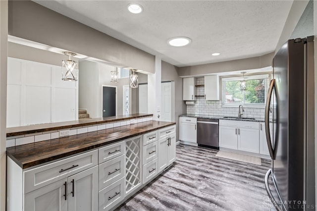 kitchen featuring butcher block counters, stainless steel appliances, a sink, decorative backsplash, and recessed lighting