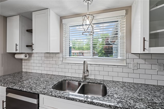 kitchen featuring a sink, open shelves, white cabinets, dark stone countertops, and pendant lighting