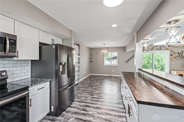 kitchen with butcher block countertops, appliances with stainless steel finishes, dark wood finished floors, white cabinets, and tasteful backsplash