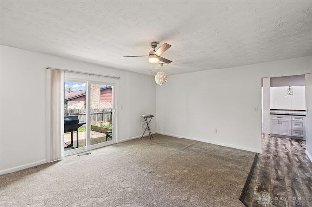 carpeted spare room featuring ceiling fan, baseboards, and a textured ceiling