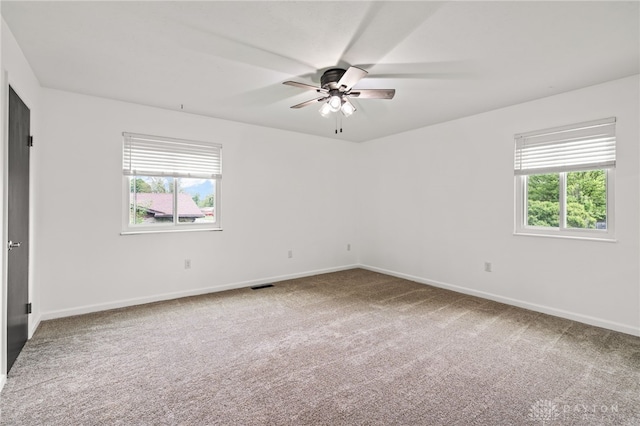 carpeted empty room with a ceiling fan and baseboards