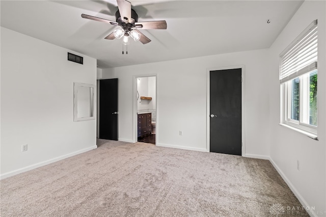 unfurnished bedroom featuring carpet, baseboards, ensuite bath, and ceiling fan