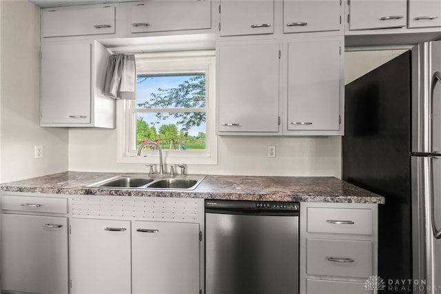 kitchen featuring appliances with stainless steel finishes, a sink, white cabinetry, and dark countertops