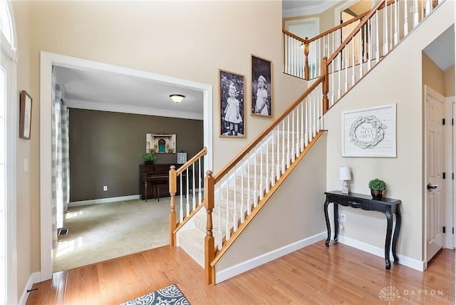 9378 Oak Brook Dr, Clearcreek Twp, OH 45458 - stairway with crown molding, wood finished floors, a towering ceiling, and baseboards