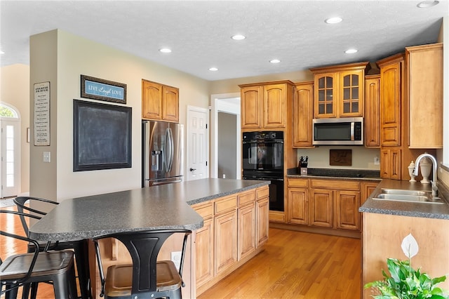 9378 Oak Brook Dr, Clearcreek Twp, OH 45458 - kitchen with appliances with stainless steel finishes, a sink, dark countertops, a center island, and light wood finished floors