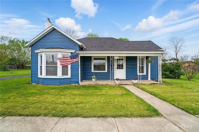 bungalow-style house featuring a front lawn, covered porch, roof with shingles, and a chimney