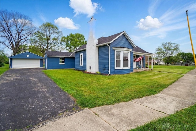 view of front of home featuring a garage, an outbuilding, a front yard, and a chimney