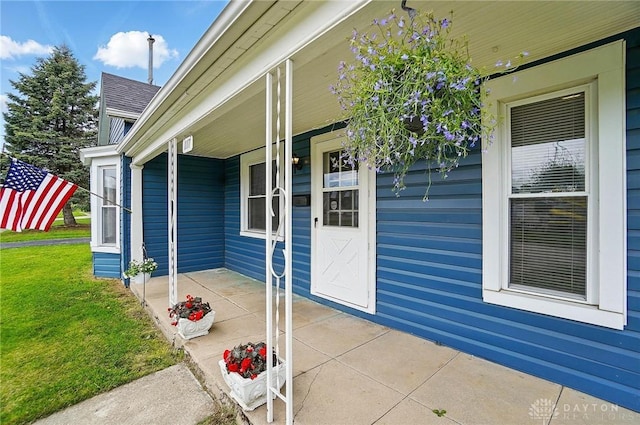 doorway to property with a lawn and a porch