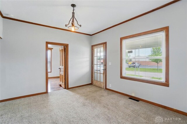 empty room featuring light colored carpet, ornamental molding, and baseboards