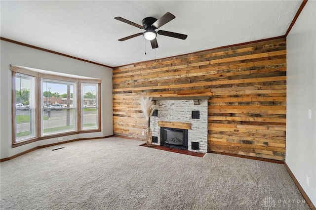unfurnished living room featuring wooden walls, baseboards, ornamental molding, ceiling fan, and carpet