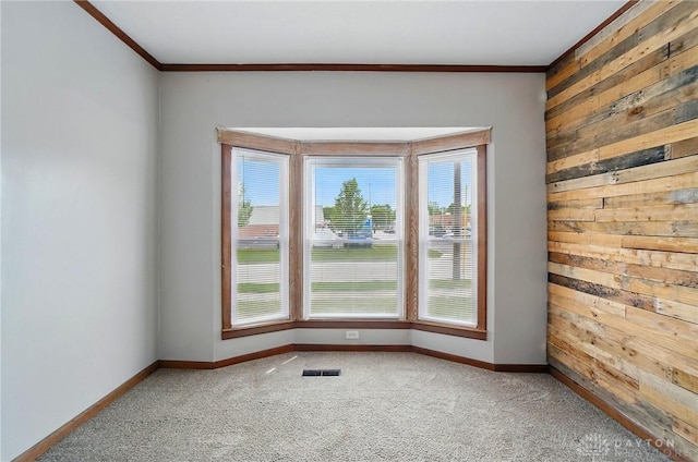 unfurnished room featuring crown molding, light colored carpet, wood walls, and baseboards