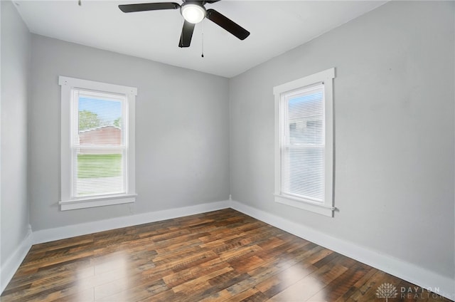 spare room with dark wood finished floors, a ceiling fan, and baseboards