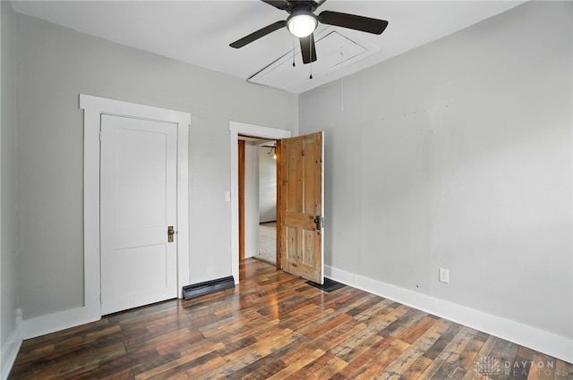 unfurnished bedroom featuring attic access, wood finished floors, baseboards, and a ceiling fan