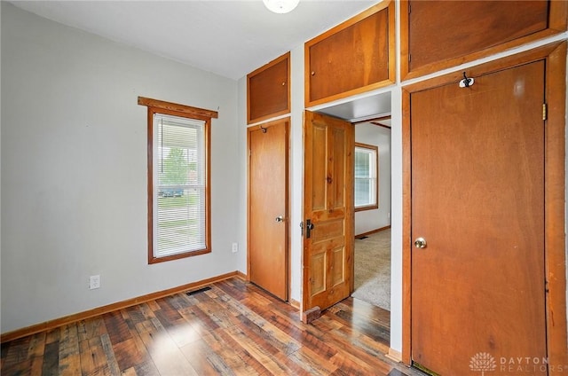 unfurnished bedroom featuring hardwood / wood-style floors, baseboards, and a closet