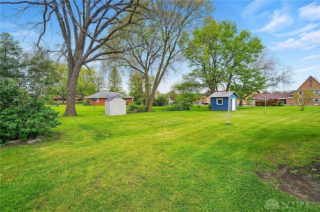 view of grassy yard featuring a storage unit and an outbuilding