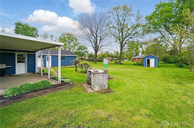 view of grassy yard with a storage shed, an outbuilding, and a carport
